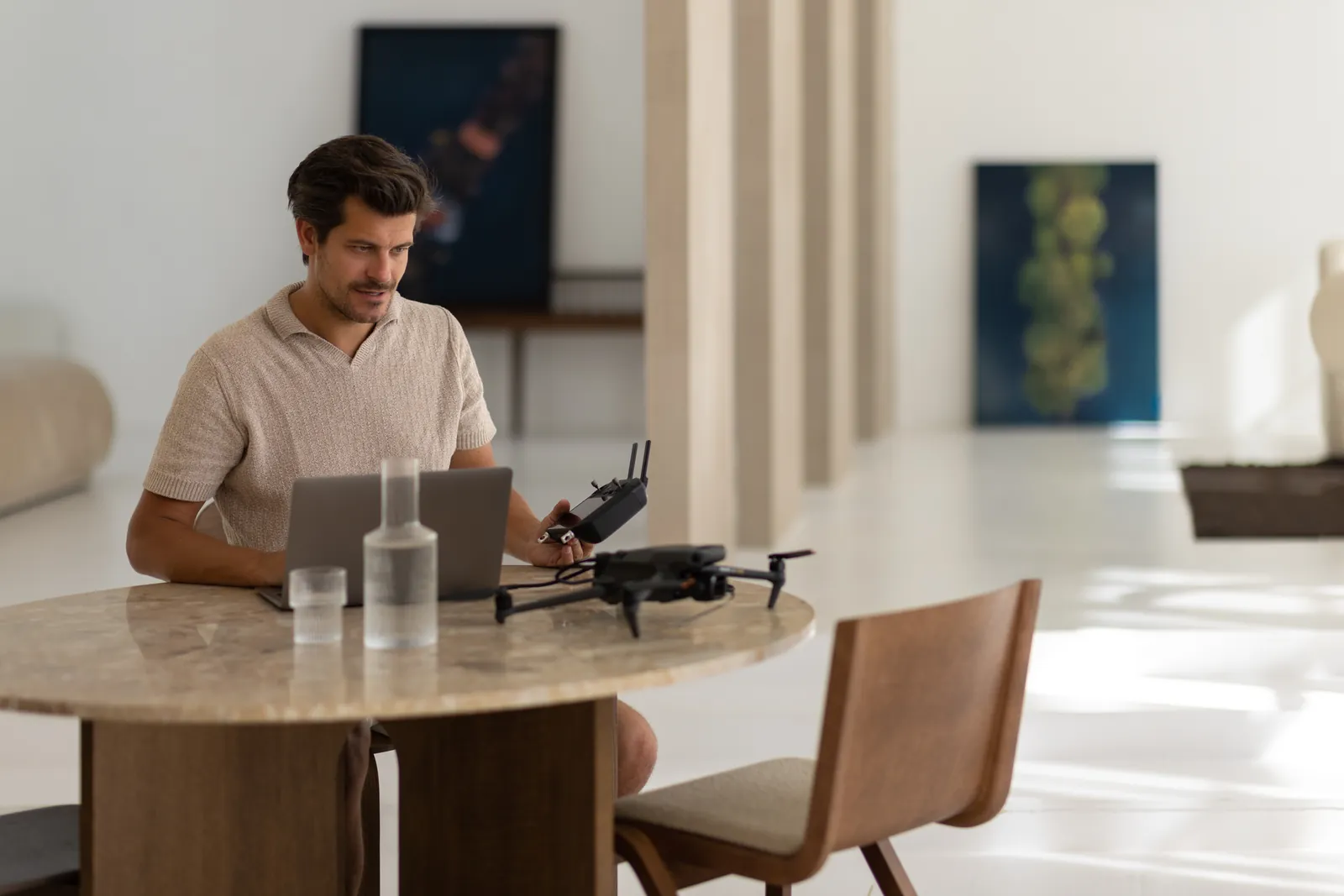 Stefan van Gils at a table with his drone, with artworks in the background